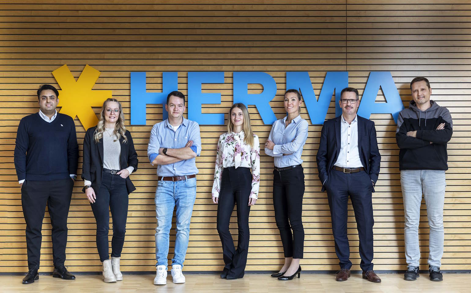 HERMA Mitarbeiter vor HERMA Logo